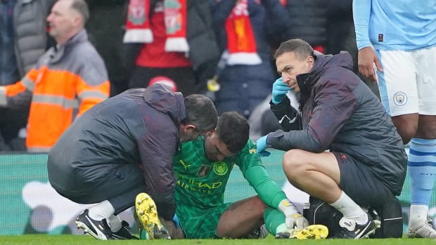 Manchester City goalkeeper Ederson pictured (center) receiving medical treatment during his team's 1-1 draw at Liverpool in March 2024